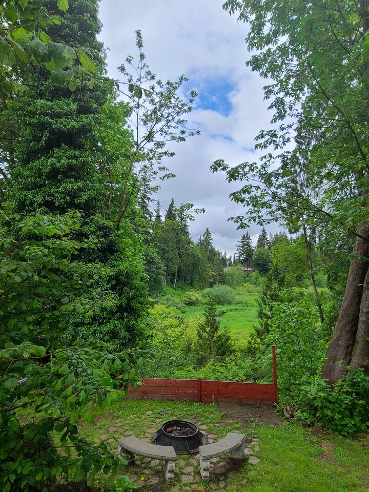 View of the creek and wooded backyard with fire pit at the Creekside Suite vacation rental in Marysville, WA